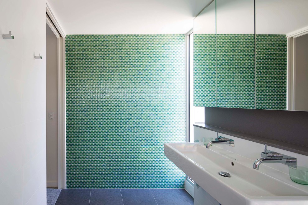 This is an example of a mid-sized contemporary master bathroom in Sydney with a one-piece toilet, green tile, mosaic tile and a wall-mount sink.