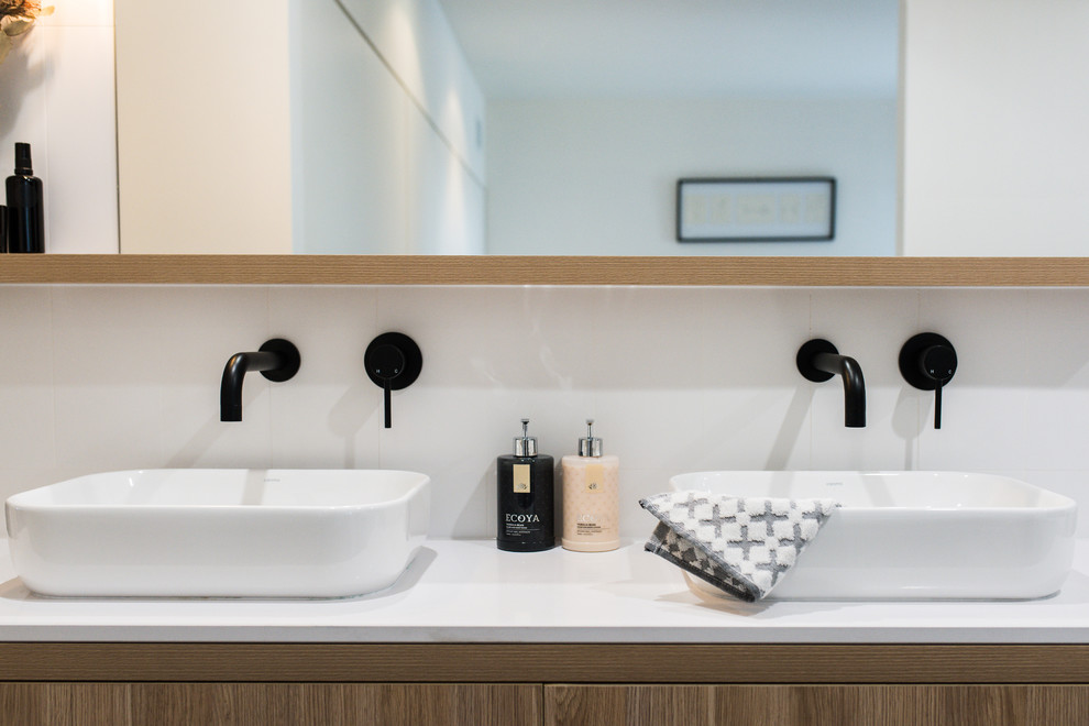 Design ideas for a large contemporary master bathroom in Melbourne with shaker cabinets, light wood cabinets, a corner tub, a shower/bathtub combo, a one-piece toilet, white tile, ceramic tile, white walls, porcelain floors, a vessel sink, engineered quartz benchtops and black floor.