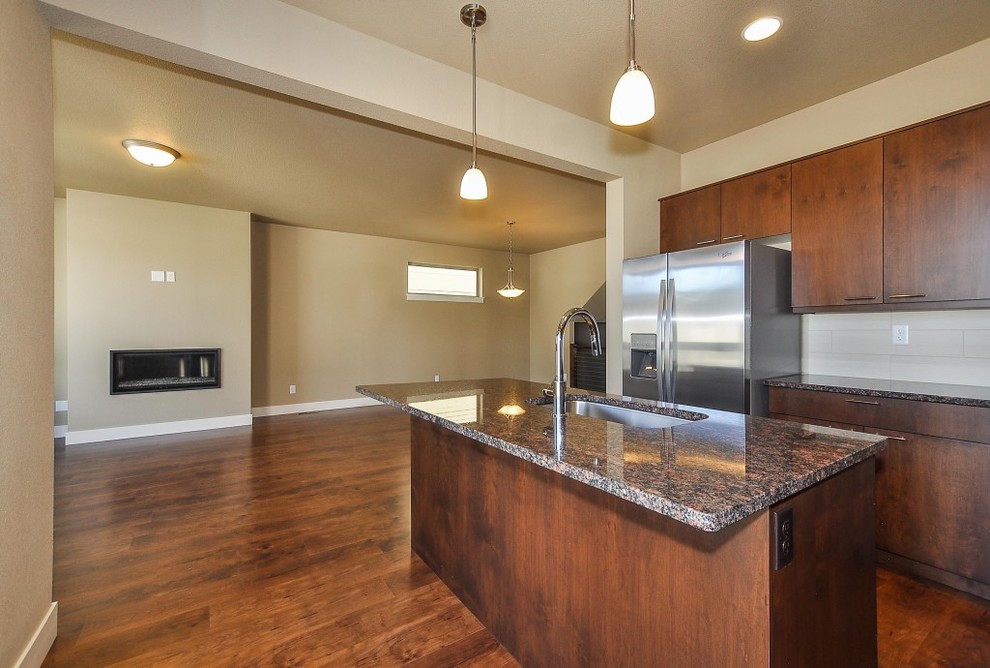 Inspiration for a large transitional l-shaped laminate floor open concept kitchen remodel in Orange County with an undermount sink, flat-panel cabinets, dark wood cabinets, granite countertops, stainless steel appliances and an island