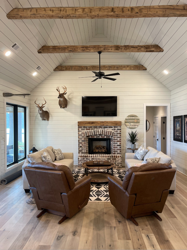This is an example of a medium sized rustic open plan living room in Los Angeles with white walls, medium hardwood flooring, a standard fireplace, a brick fireplace surround, a wall mounted tv, a timber clad ceiling and tongue and groove walls.