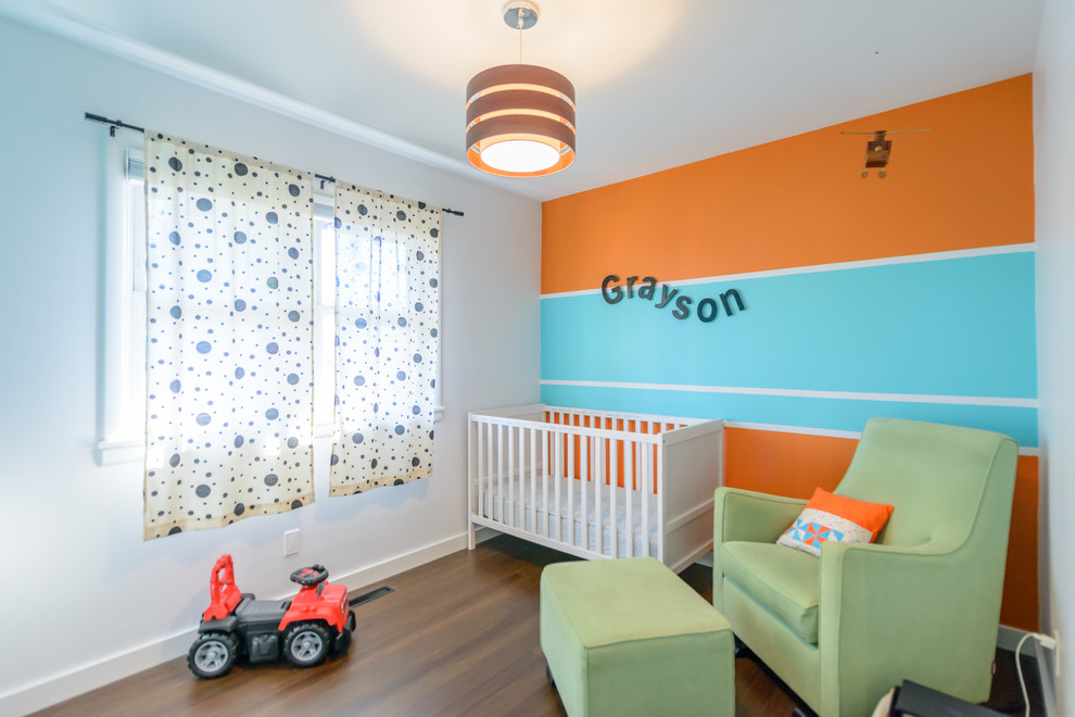 Design ideas for a mid-sized modern nursery for boys in Toronto with medium hardwood floors and multi-coloured walls.