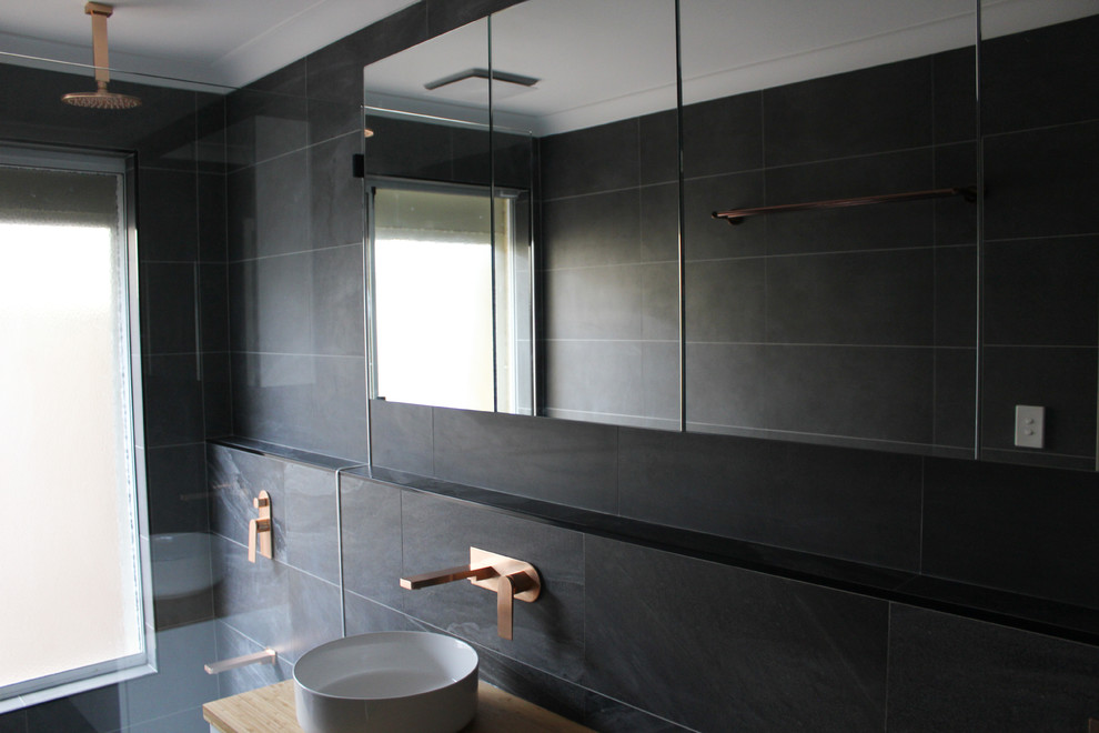 Design ideas for a mid-sized contemporary kids bathroom in Perth with furniture-like cabinets, white cabinets, an alcove tub, a shower/bathtub combo, black tile, porcelain tile, black walls, porcelain floors, a vessel sink, wood benchtops, black floor and multi-coloured benchtops.