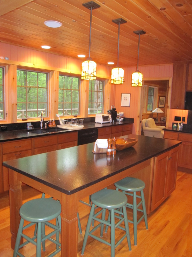 Inspiration for a medium tone wood floor kitchen remodel with an undermount sink, recessed-panel cabinets, medium tone wood cabinets, granite countertops, black backsplash and black appliances