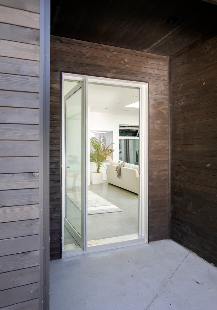 Photo of a large modern front door in Vancouver with brown walls, concrete floors, a pivot front door and grey floor.