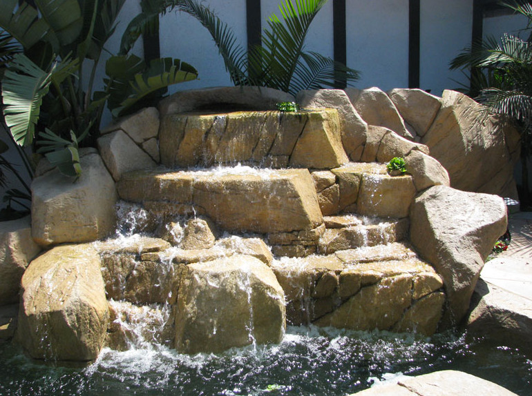 Inspiration for a tropical custom-shaped aboveground pool in Orange County with a water feature.
