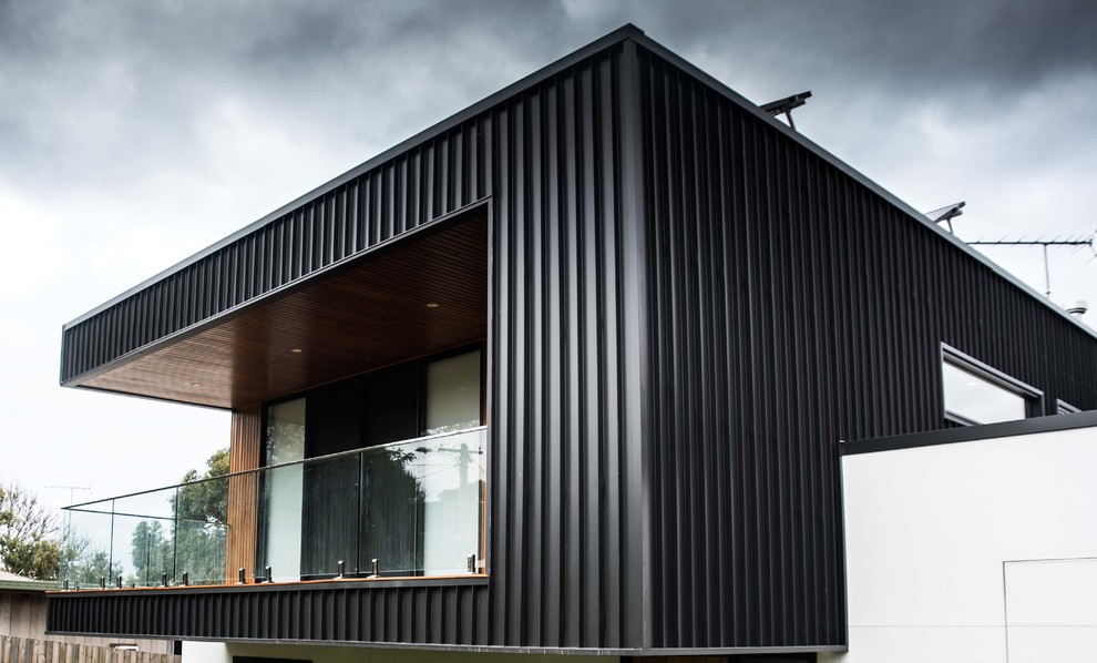 Design ideas for a large contemporary two-storey black house exterior in Geelong with metal siding, a flat roof and a metal roof.