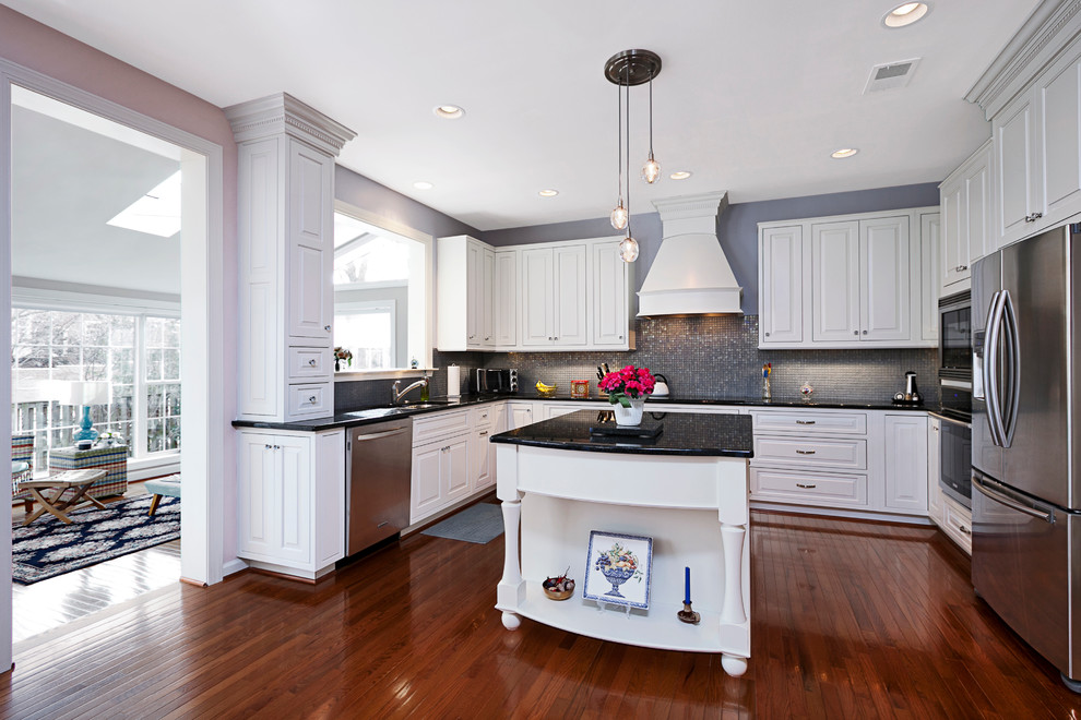 Photo of a traditional u-shaped kitchen in DC Metro with an undermount sink, raised-panel cabinets, white cabinets, grey splashback and stainless steel appliances.