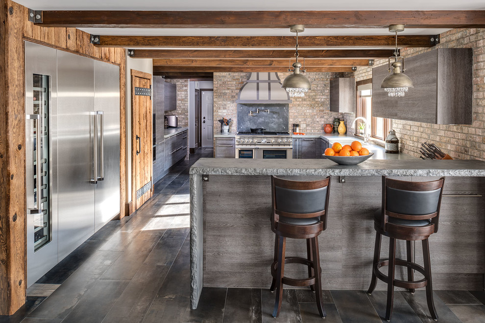 Photo of a large country l-shaped separate kitchen in New York with a farmhouse sink, grey cabinets, concrete benchtops, brick splashback, stainless steel appliances, porcelain floors, a peninsula, flat-panel cabinets, multi-coloured splashback, grey floor, grey benchtop and exposed beam.
