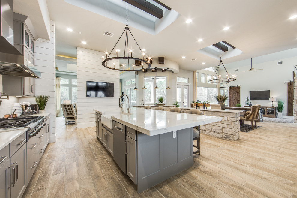 This is an example of a large country eat-in kitchen in Dallas with shaker cabinets, grey cabinets, quartz benchtops, white splashback, ceramic splashback and multiple islands.