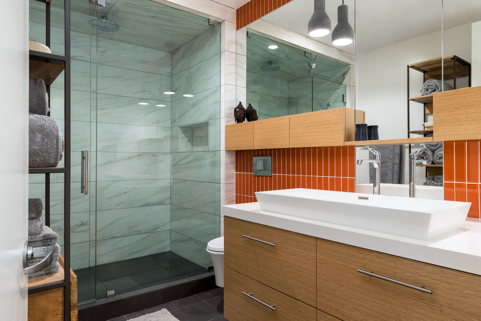 Design ideas for a small eclectic master bathroom in San Diego with furniture-like cabinets, light wood cabinets, an alcove shower, a wall-mount toilet, orange tile, glass tile, white walls, porcelain floors, a trough sink, engineered quartz benchtops, grey floor and a hinged shower door.