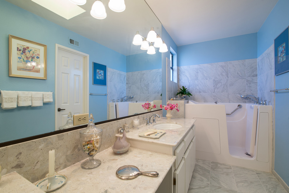 Design ideas for a mid-sized modern master bathroom in San Diego with an undermount sink, raised-panel cabinets, white cabinets, marble benchtops, a freestanding tub, a one-piece toilet, white tile, ceramic tile, blue walls and ceramic floors.