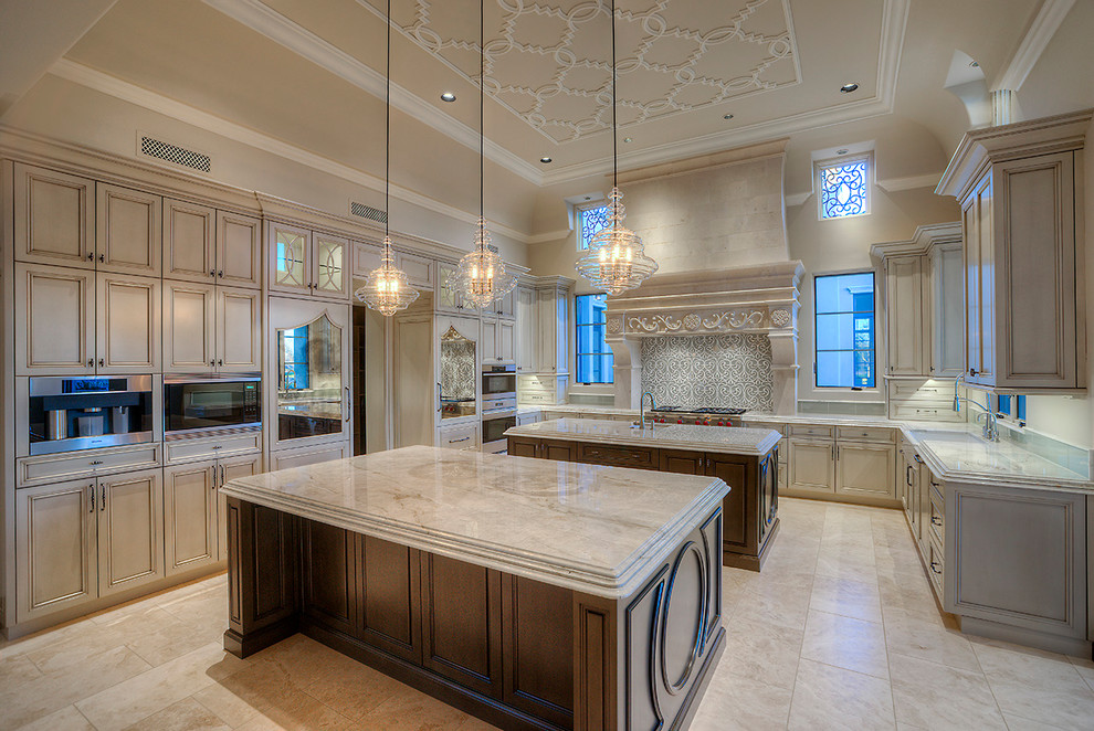 Photo of an expansive traditional u-shaped separate kitchen in Phoenix with a farmhouse sink, recessed-panel cabinets, brown cabinets, quartzite benchtops, multi-coloured splashback, porcelain splashback, stainless steel appliances, marble floors, multiple islands, beige floor and beige benchtop.