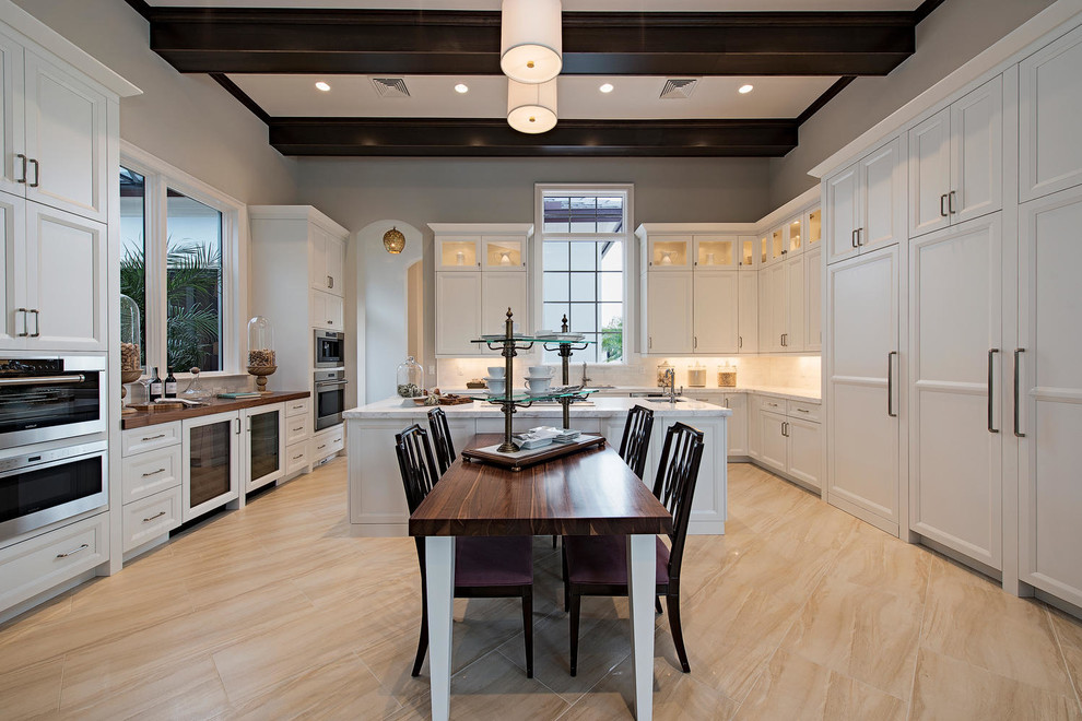Eat-in kitchen - transitional eat-in kitchen idea in Miami with recessed-panel cabinets, white cabinets, white backsplash, stainless steel appliances and an island