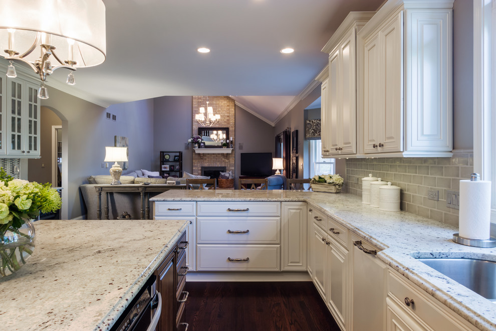 Example of a large transitional u-shaped dark wood floor kitchen design in Chicago with a double-bowl sink, raised-panel cabinets, white cabinets, granite countertops, gray backsplash, subway tile backsplash, stainless steel appliances and an island