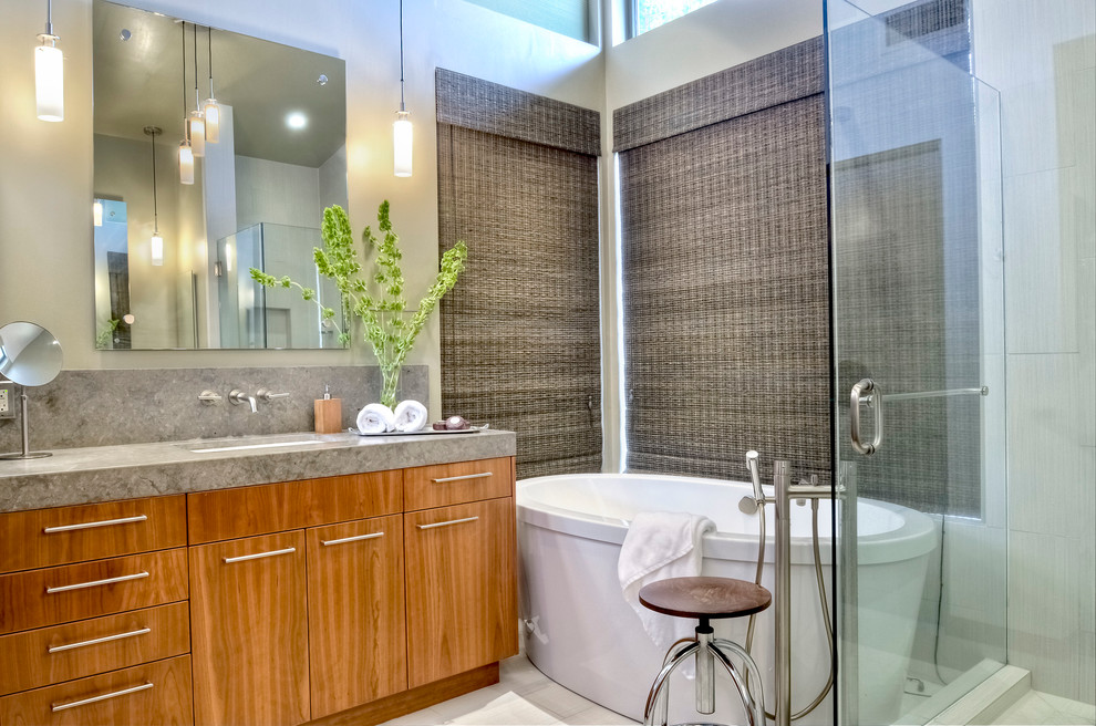 Design ideas for a mid-sized contemporary master bathroom in San Diego with an undermount sink, flat-panel cabinets, medium wood cabinets, limestone benchtops, a freestanding tub, an open shower, a one-piece toilet, white tile, porcelain tile, grey walls and porcelain floors.