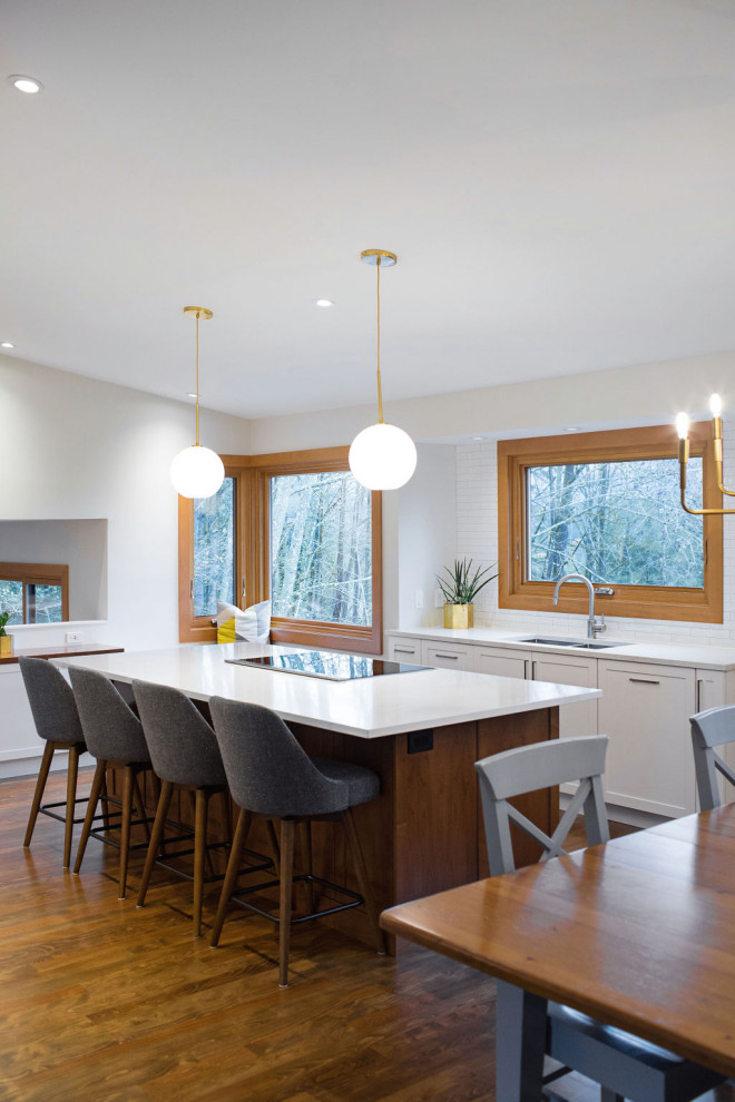 Inspiration for a mid-sized craftsman medium tone wood floor kitchen remodel in Vancouver with shaker cabinets, white cabinets, quartz countertops, white backsplash, porcelain backsplash, stainless steel appliances, an island and white countertops