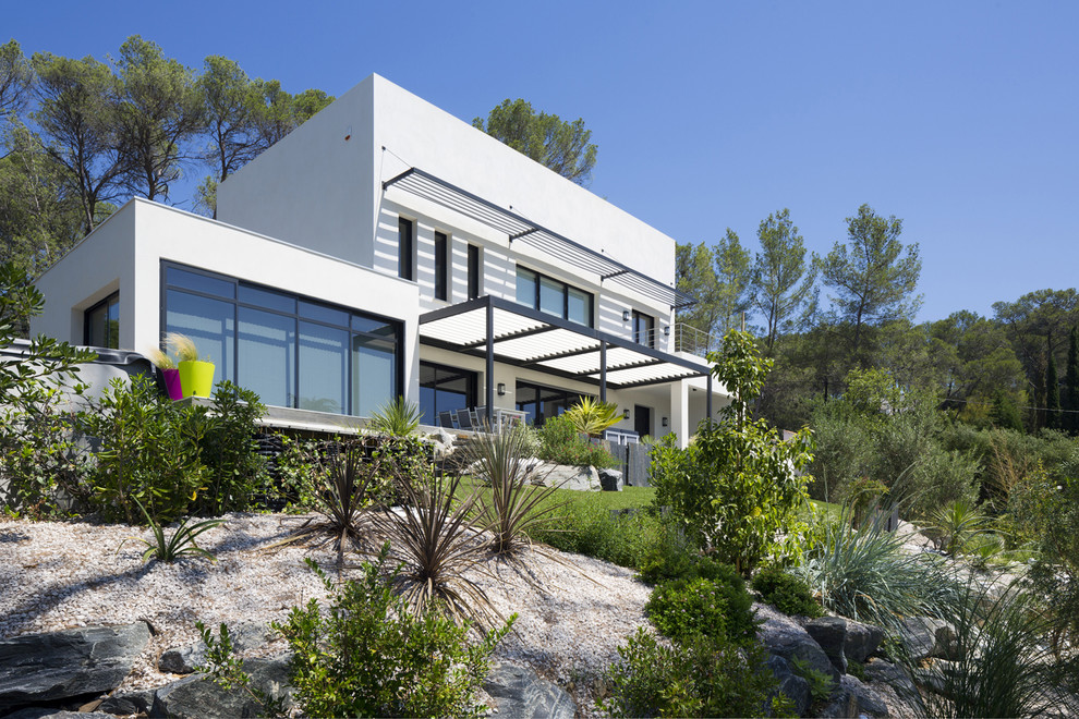 This is an example of a contemporary split-level beige house exterior in Marseille with mixed siding, a flat roof and a mixed roof.