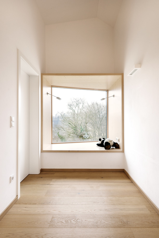 This is an example of a large contemporary hallway in Munich with white walls and light hardwood floors.