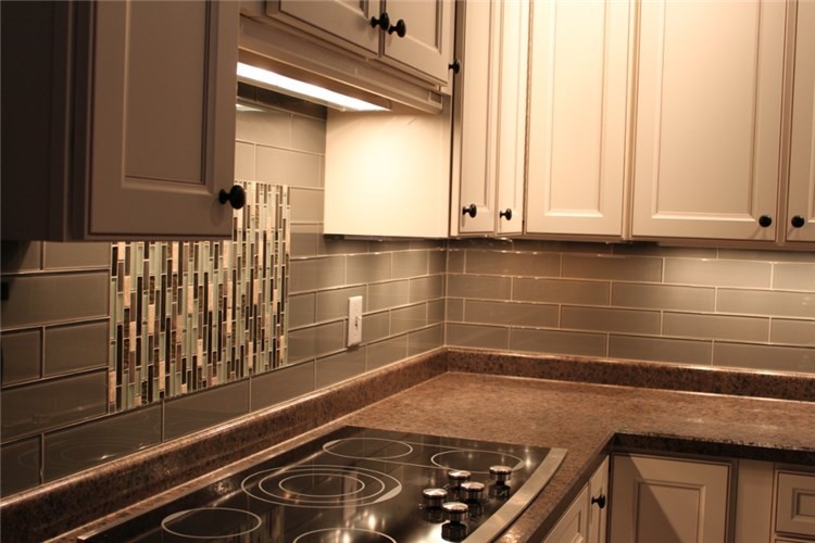 Example of a mid-sized transitional l-shaped kitchen design in Milwaukee with mosaic tile backsplash, recessed-panel cabinets, white cabinets, granite countertops, gray backsplash and stainless steel appliances