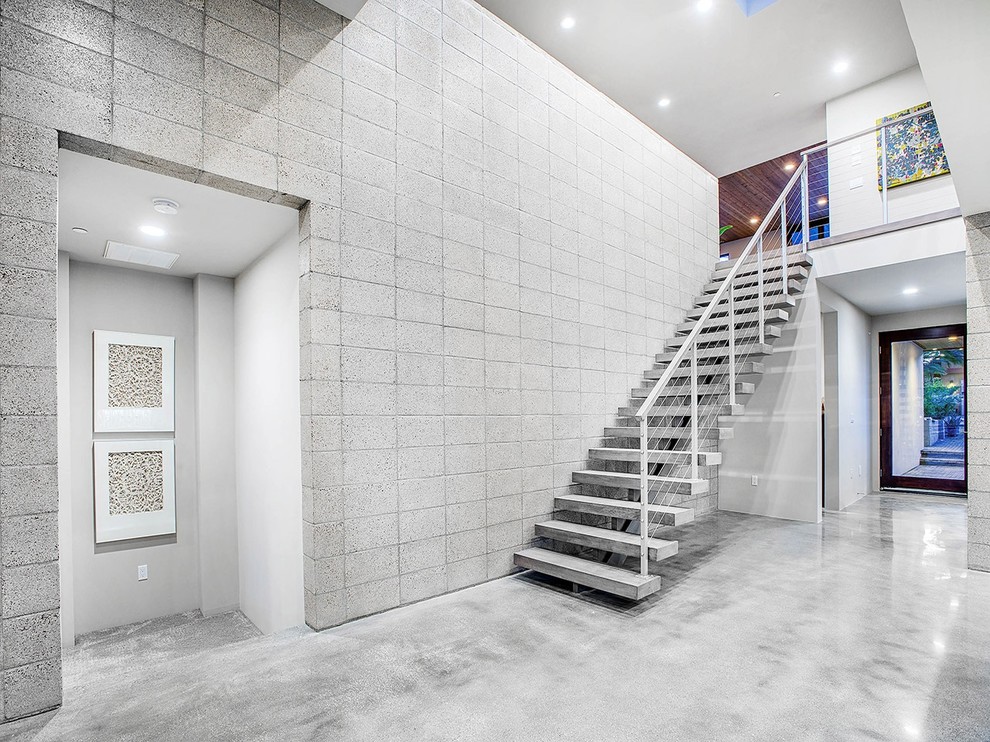 Photo of a large contemporary concrete straight staircase in San Diego with open risers and cable railing.