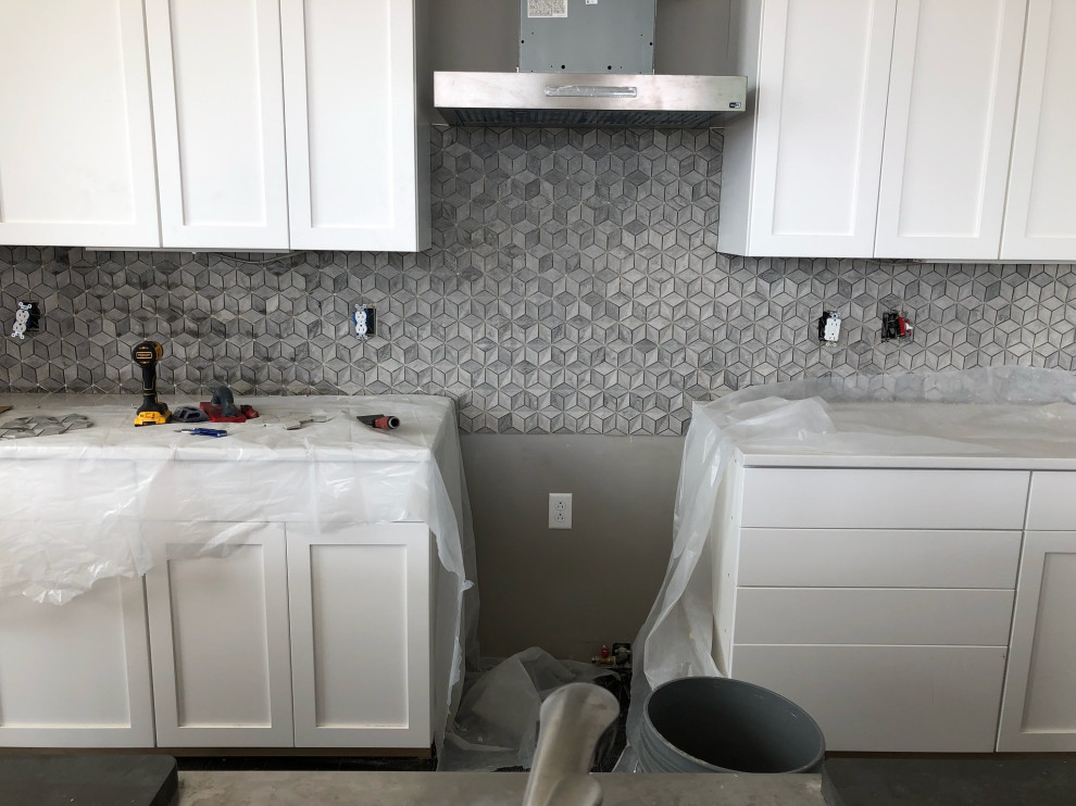 Kitchen - transitional kitchen idea with shaker cabinets, white cabinets, wood countertops, gray backsplash, mosaic tile backsplash, stainless steel appliances, an island and white countertops
