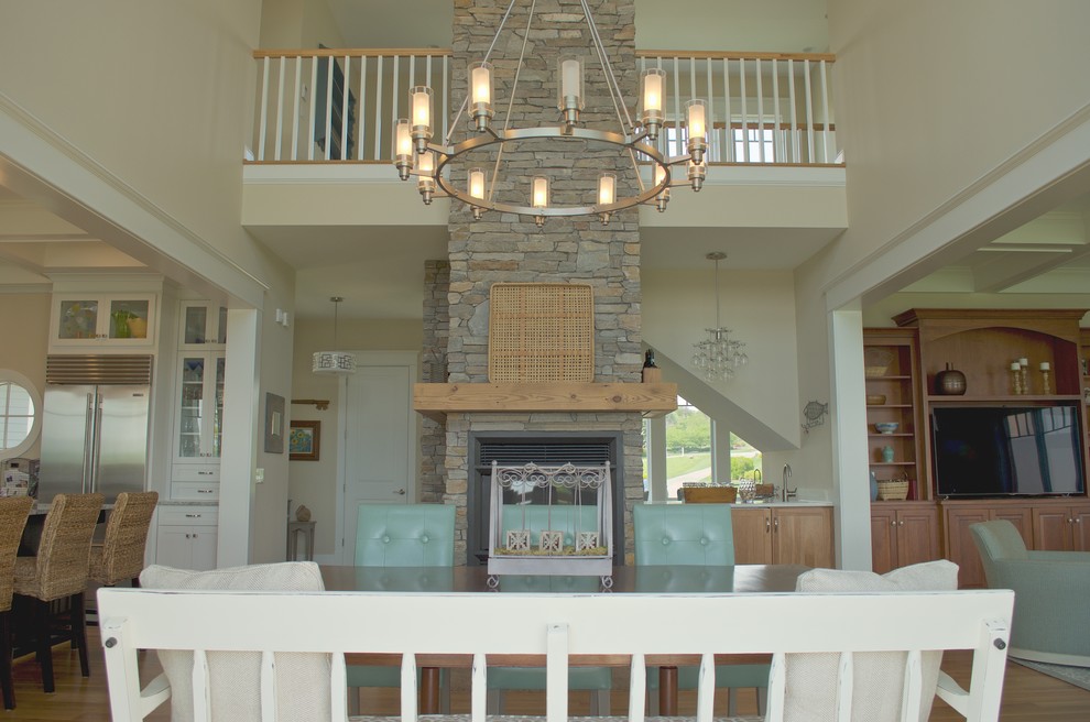 Inspiration for a large beach style open plan dining in Other with light hardwood floors, a standard fireplace, a stone fireplace surround and beige walls.