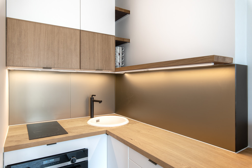 Design ideas for a small contemporary l-shaped open plan kitchen in Paris with a single-bowl sink, beaded inset cabinets, white cabinets, wood benchtops, brown splashback, glass sheet splashback, panelled appliances, light hardwood floors, no island, brown floor and brown benchtop.