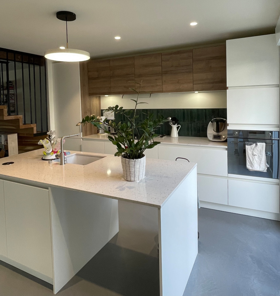 This is an example of a large modern single-wall open plan kitchen in Toulouse with an integrated sink, beaded inset cabinets, stainless steel cabinets, green splashback, porcelain splashback, coloured appliances, concrete floors, with island, grey floor, quartzite benchtops and beige benchtop.