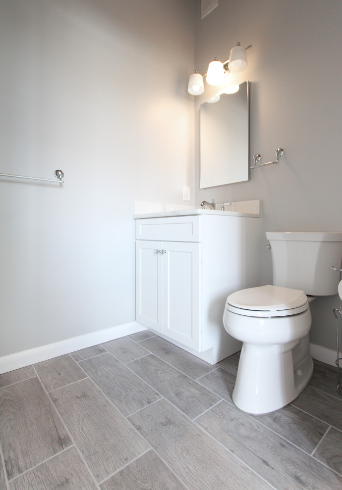 Mid-sized contemporary kids bathroom in Philadelphia with recessed-panel cabinets, white cabinets, an alcove shower, a two-piece toilet, gray tile, ceramic tile, grey walls, ceramic floors, an undermount sink, engineered quartz benchtops, grey floor, a sliding shower screen and white benchtops.