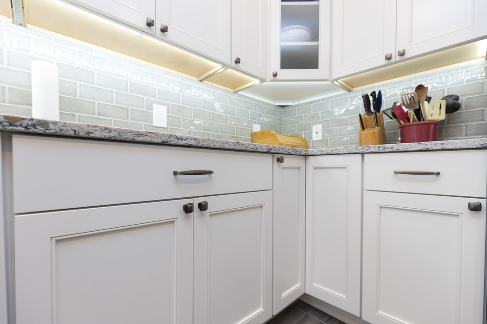Enclosed kitchen - mid-sized transitional l-shaped porcelain tile and brown floor enclosed kitchen idea in San Diego with an undermount sink, beaded inset cabinets, white cabinets, granite countertops, gray backsplash, ceramic backsplash, stainless steel appliances, no island and gray countertops