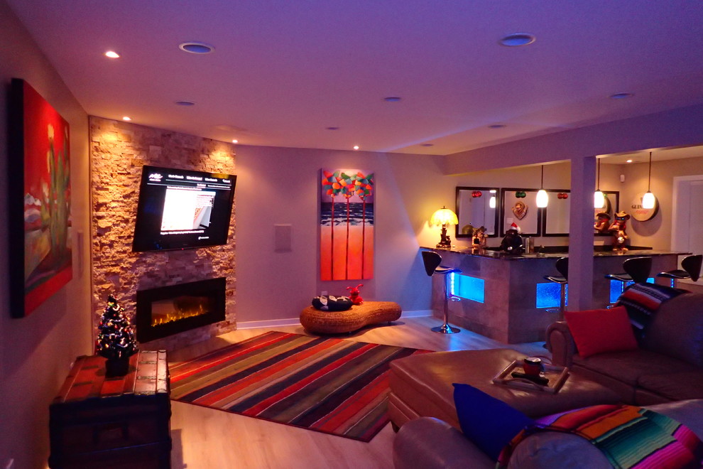 Inspiration for a large eclectic walk-out laminate floor and beige floor basement remodel with beige walls, a hanging fireplace and a stone fireplace