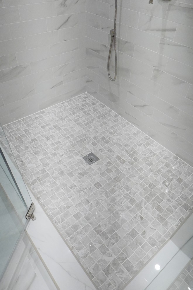 Example of a large transitional master white tile and porcelain tile porcelain tile and white floor freestanding bathtub design with shaker cabinets, white cabinets, a two-piece toilet, beige walls, an undermount sink, marble countertops, a hinged shower door and white countertops