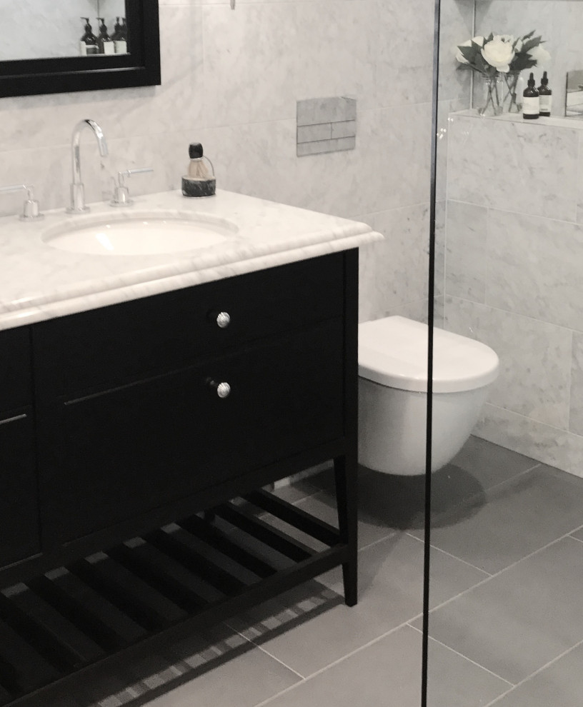 Design ideas for a mid-sized transitional bathroom in Melbourne with black cabinets, a freestanding tub, an open shower, a wall-mount toilet, gray tile, marble, grey walls, ceramic floors, an undermount sink, marble benchtops, grey floor, an open shower and grey benchtops.