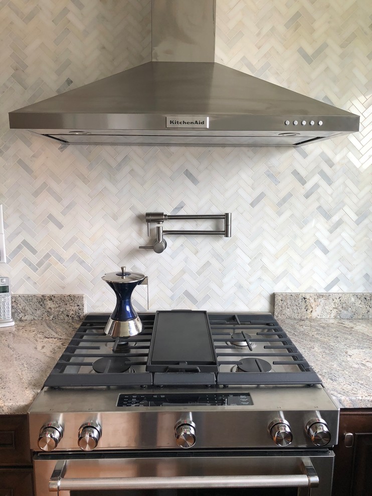 Eat-in kitchen - mid-sized traditional l-shaped light wood floor and brown floor eat-in kitchen idea with an undermount sink, raised-panel cabinets, dark wood cabinets, granite countertops, multicolored backsplash, ceramic backsplash, stainless steel appliances, an island and multicolored countertops