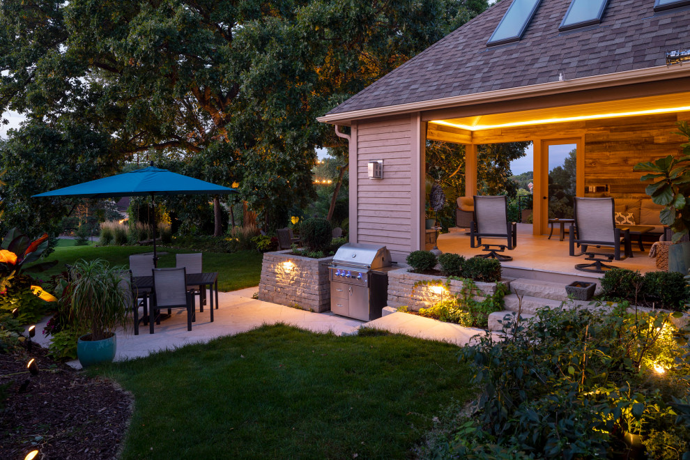 This is an example of a mid-sized traditional backyard verandah in Minneapolis with with fireplace, natural stone pavers and a roof extension.