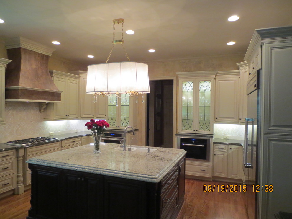 This is an example of a large traditional u-shaped eat-in kitchen in Atlanta with a double-bowl sink, raised-panel cabinets, white cabinets, granite benchtops, beige splashback, medium hardwood floors, with island and stainless steel appliances.