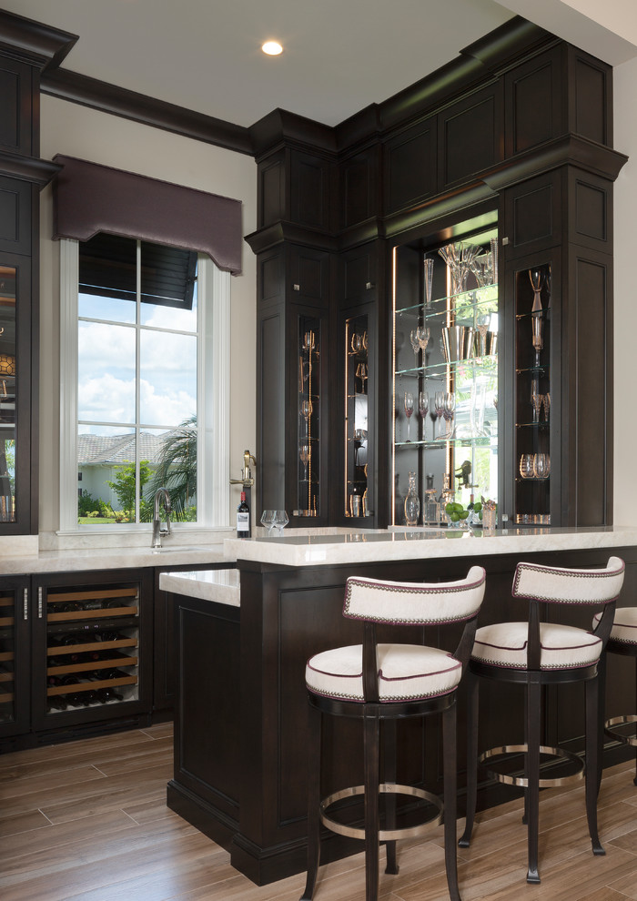 Inspiration for a mid-sized contemporary u-shaped seated home bar in Miami with an undermount sink, glass-front cabinets and dark wood cabinets.