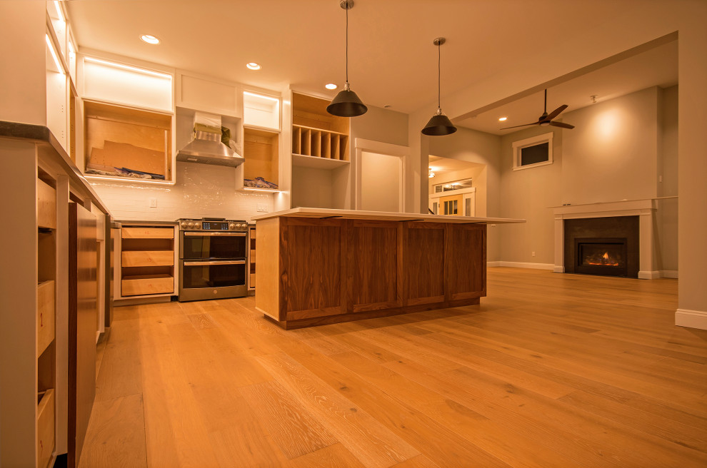 This is an example of a large transitional l-shaped eat-in kitchen in Seattle with an undermount sink, flat-panel cabinets, medium wood cabinets, quartzite benchtops, white splashback, subway tile splashback, stainless steel appliances, medium hardwood floors, with island, grey benchtop and vaulted.