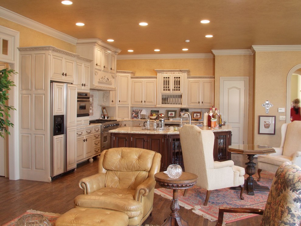 Example of a large l-shaped medium tone wood floor kitchen pantry design with an undermount sink, raised-panel cabinets, white cabinets, granite countertops, beige backsplash, matchstick tile backsplash, stainless steel appliances and an island