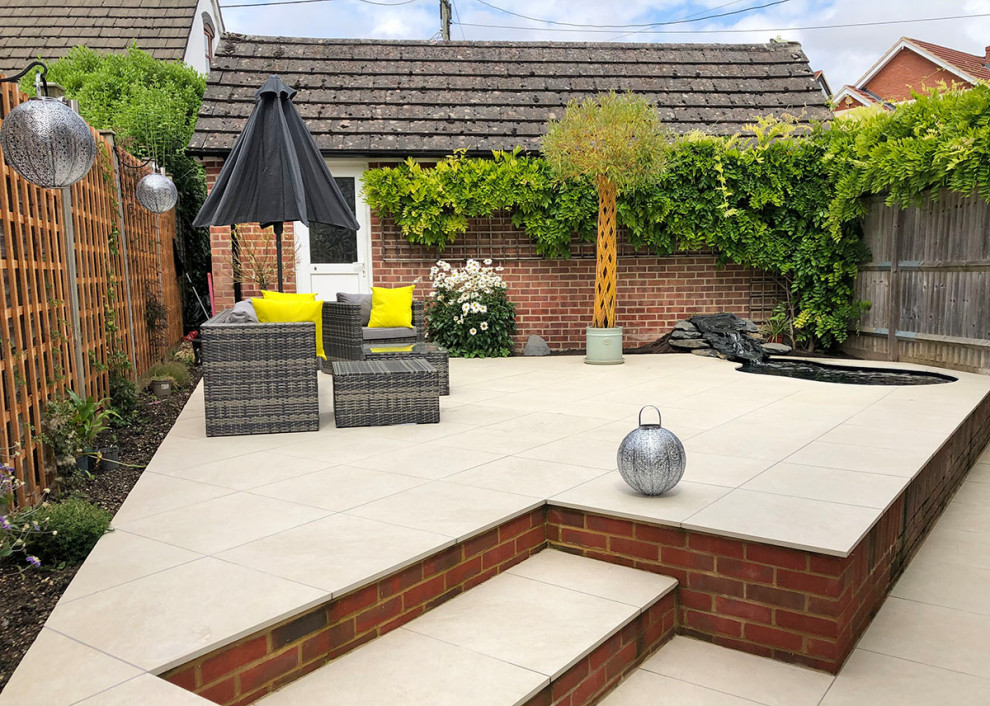 Inspiration for a mid-sized contemporary backyard patio in Essex with tile.
