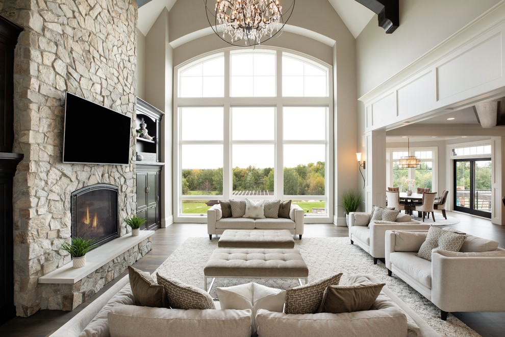 Design ideas for an expansive traditional open concept living room in Minneapolis with medium hardwood floors, a standard fireplace, a stone fireplace surround, brown floor and beige walls.