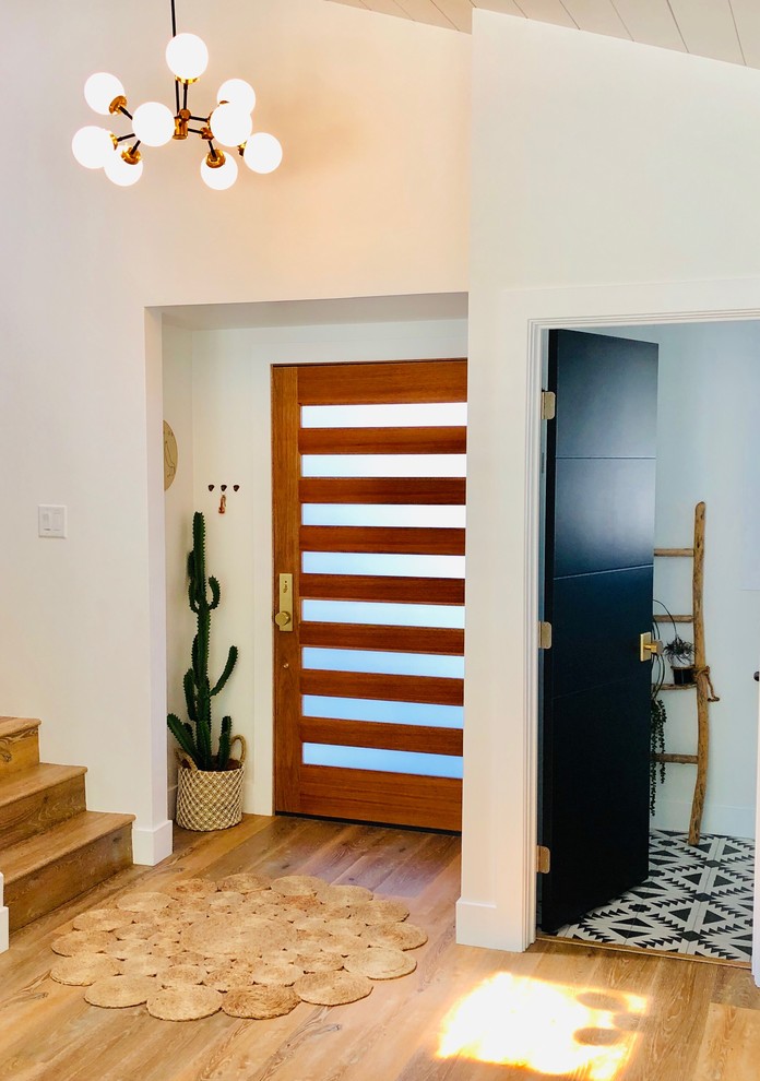 Inspiration for a large eclectic front door in Los Angeles with white walls, laminate floors, a single front door, a medium wood front door and brown floor.