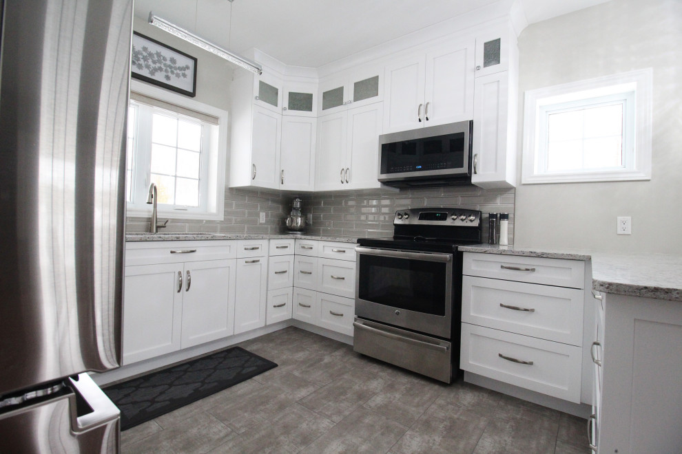 Example of an u-shaped kitchen design with shaker cabinets, white cabinets, quartzite countertops, gray backsplash, subway tile backsplash, a peninsula and gray countertops