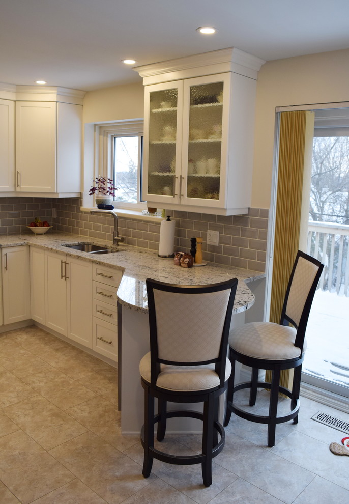 Enclosed kitchen - mid-sized transitional u-shaped ceramic tile enclosed kitchen idea in Ottawa with an undermount sink, shaker cabinets, white cabinets, granite countertops, gray backsplash, glass tile backsplash, stainless steel appliances and a peninsula