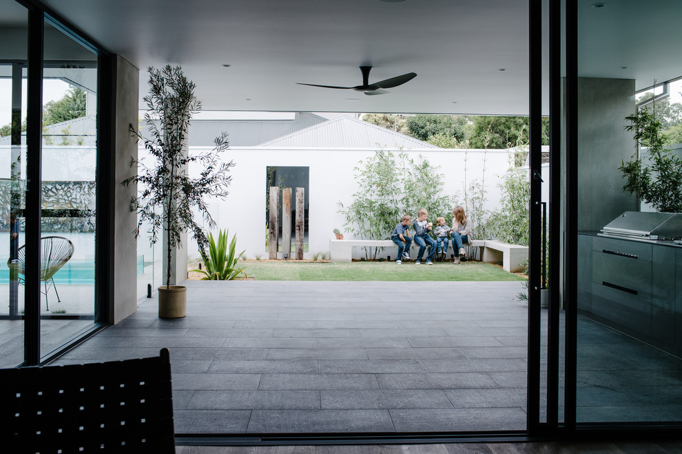Large contemporary backyard patio in Adelaide with an outdoor kitchen, natural stone pavers and a roof extension.