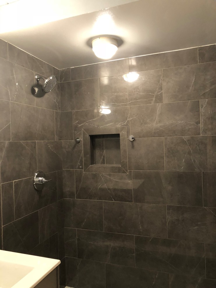 Inspiration for a mid-sized transitional 3/4 bathroom in Chicago with flat-panel cabinets, grey cabinets, an alcove shower, a two-piece toilet, gray tile, slate, grey walls, marble floors, an integrated sink, solid surface benchtops and grey floor.