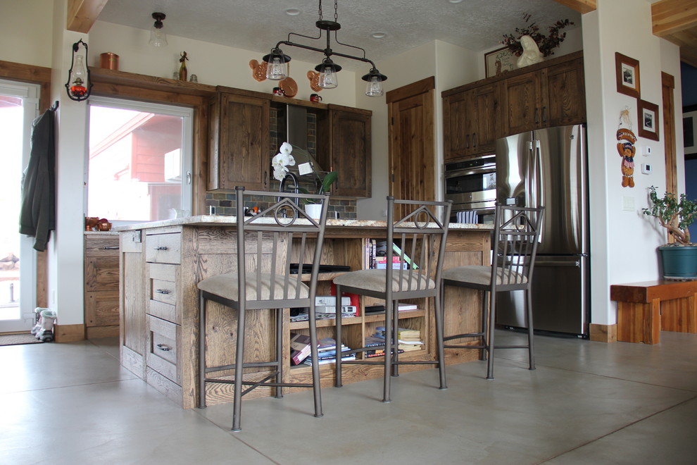 Mid-sized country l-shaped open plan kitchen in Salt Lake City with a farmhouse sink, distressed cabinets, granite benchtops, multi-coloured splashback, stone tile splashback, stainless steel appliances, concrete floors and with island.