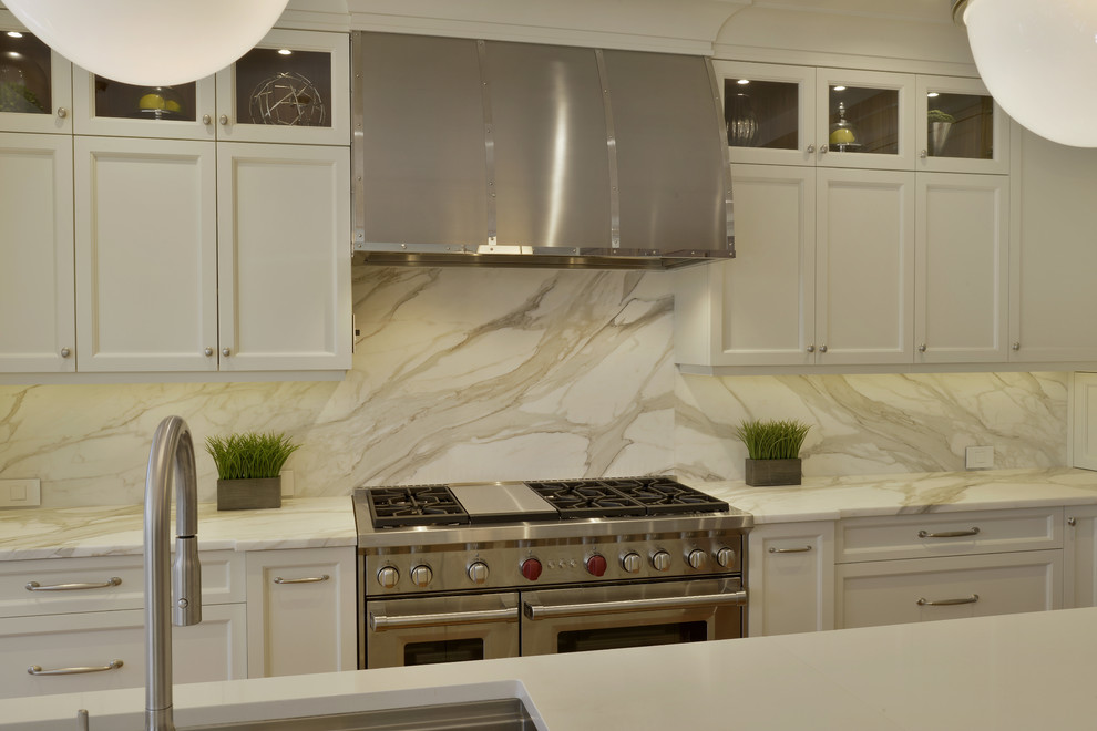 Open concept kitchen - large transitional l-shaped medium tone wood floor and brown floor open concept kitchen idea in New York with an undermount sink, glass-front cabinets, white cabinets, marble countertops, white backsplash, marble backsplash, stainless steel appliances and an island