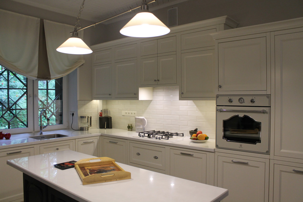 Photo of a large traditional l-shaped open plan kitchen in Moscow with an undermount sink, raised-panel cabinets, white cabinets, quartz benchtops, white splashback, porcelain splashback, white appliances, porcelain floors, with island, beige floor, white benchtop and recessed.
