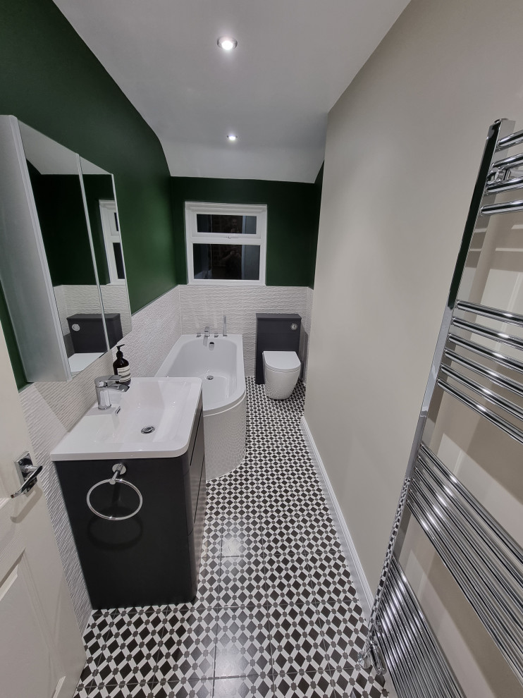 Mid-sized transitional kids bathroom in West Midlands with flat-panel cabinets, grey cabinets, a drop-in tub, an alcove shower, a one-piece toilet, white tile, porcelain tile, beige walls, porcelain floors, multi-coloured floor, a hinged shower door, a single vanity and a freestanding vanity.